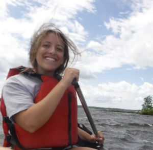 A picture of Isanne Goldberg in a red life jacket paddling a canoe